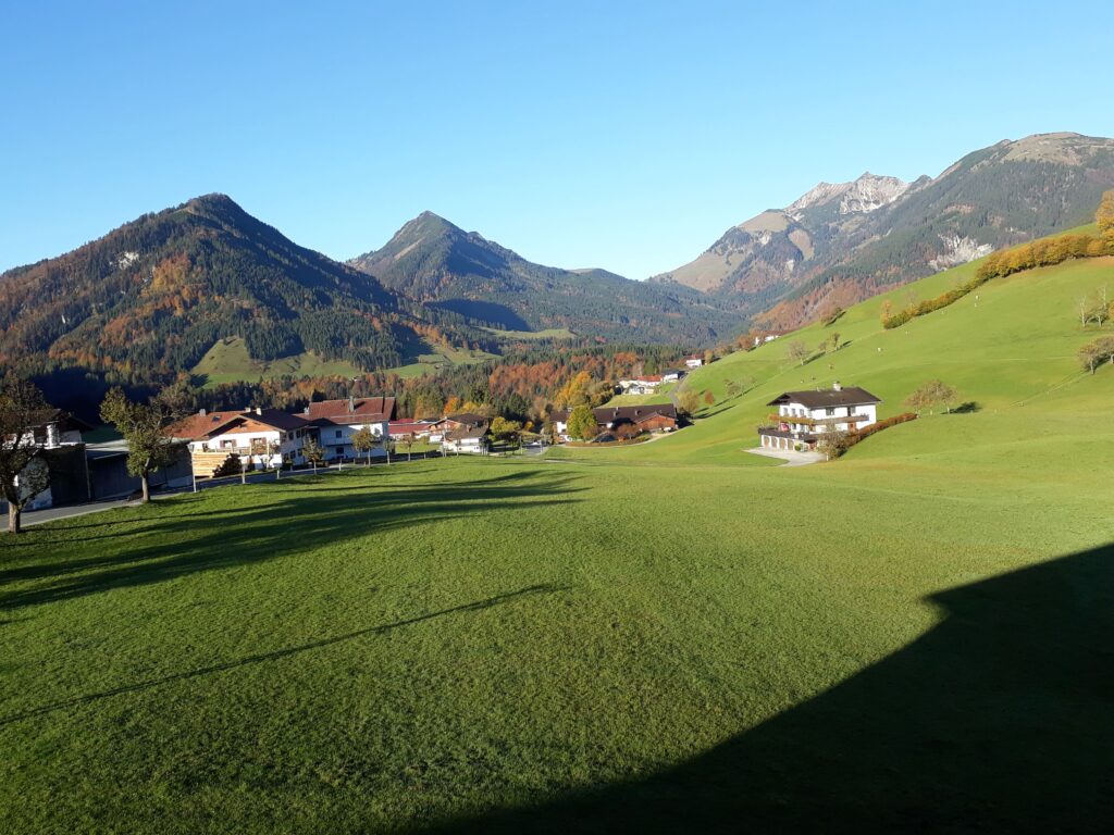 Blick auf Berge und Almhütte mit grüner Wiese im Vordergrund